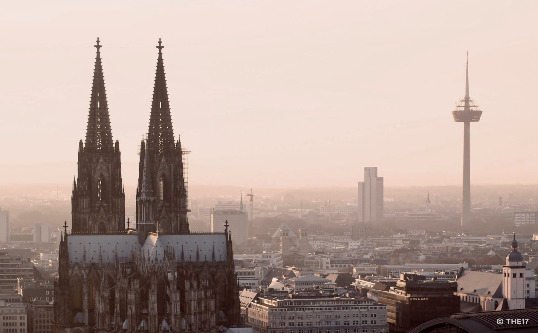 Vista de la catedral de Colonia con dos altas agujas y el paisaje urbano de fondo al anochecer.
