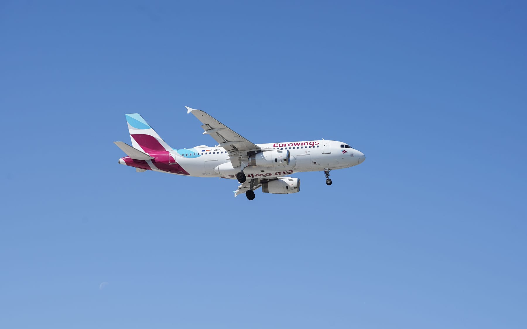 Eurowings Passagierflugzeug mit ausgefahrenem Fahrwerk fliegt vor klarem blauem Himmel.